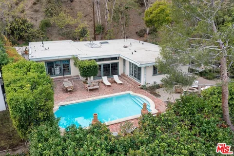 an aerial view of residential house with outdoor space and trees all around