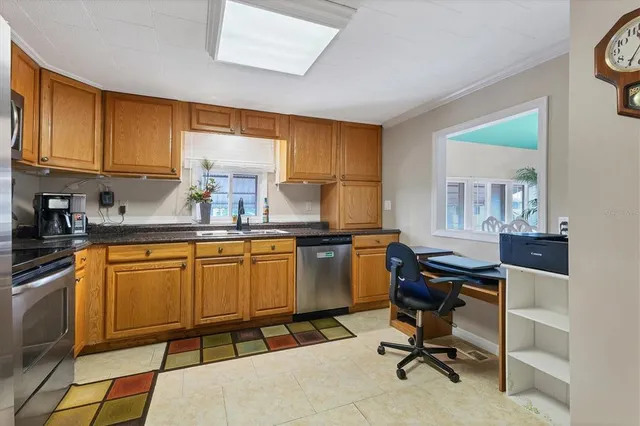 a kitchen with stainless steel appliances granite countertop sink window and white cabinets