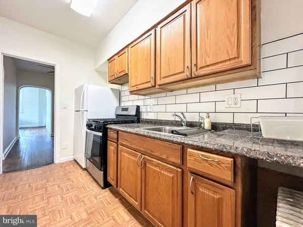 a kitchen with granite countertop stainless steel appliances a sink stove refrigerator and cabinets