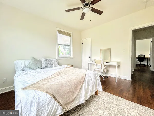 a spacious bedroom with a bed a table and wooden floor