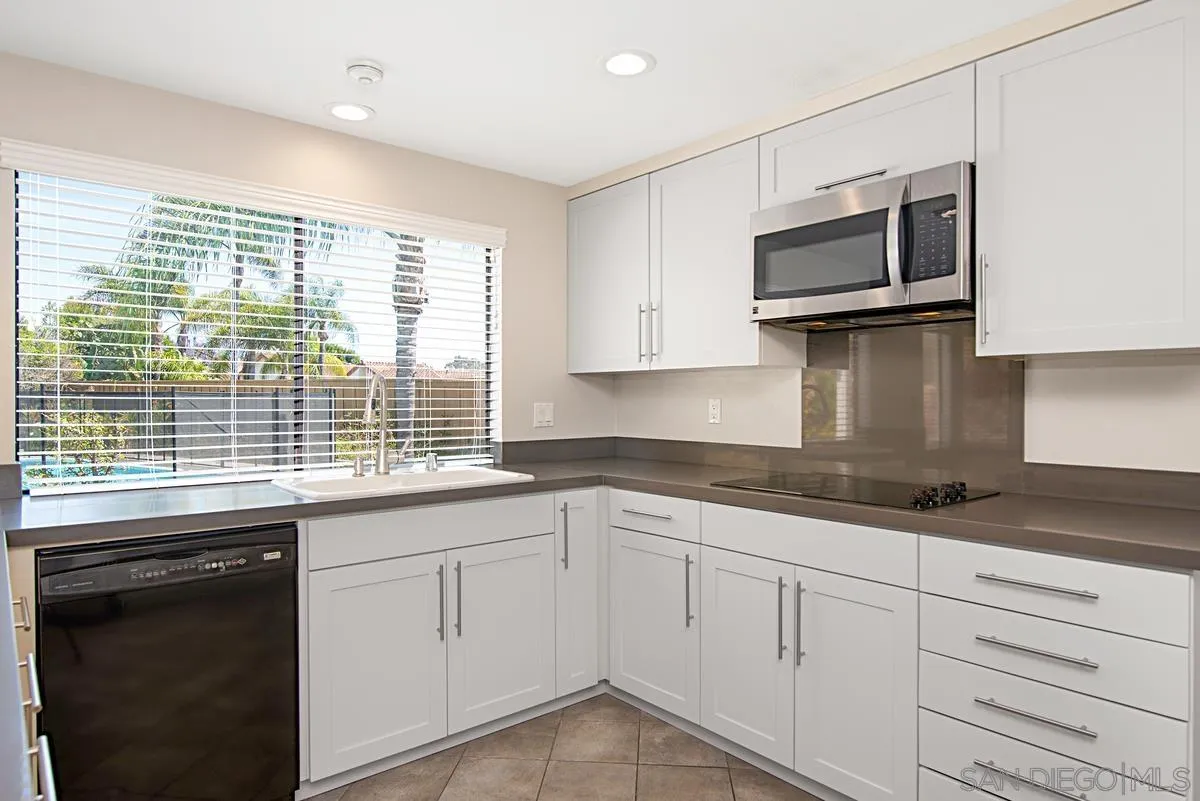 4031 Grayson Drive San Diego, CA 92130 - Photo 13 of 40 a kitchen with granite countertop white cabinets and black stainless steel appliances