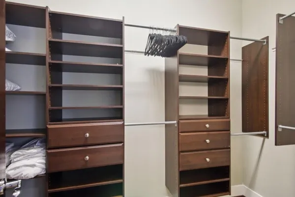 a walk in closet with wooden floor