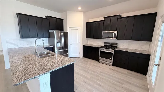a kitchen with kitchen island granite countertop stainless steel appliances and wooden cabinets