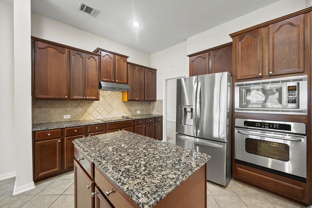 207 Leonard Way Fate, TX 75087 - Photo 3 of 31 a kitchen with stainless steel appliances granite countertop a stove refrigerator and cabinets