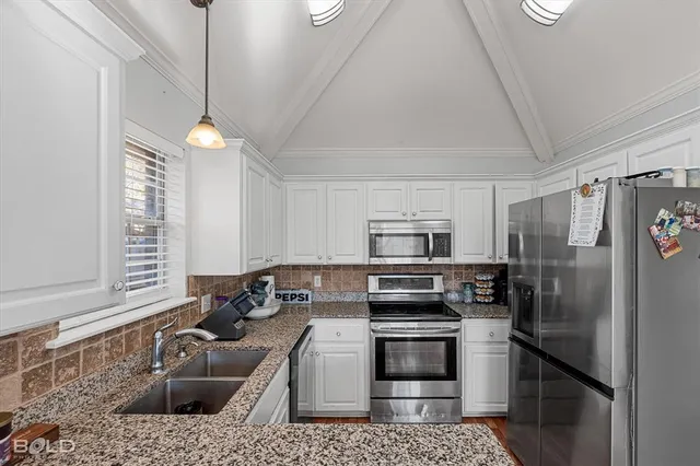 a kitchen with stainless steel appliances granite countertop a refrigerator a stove and a sink