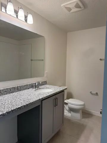 a bathroom with a granite countertop sink a toilet and a mirror
