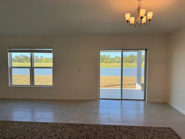 an empty room with chandelier fan and windows