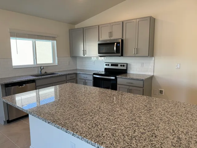 a kitchen with stainless steel appliances granite countertop a sink stove and microwave