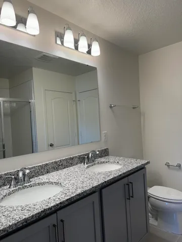 a bathroom with a granite countertop sink a toilet and a mirror