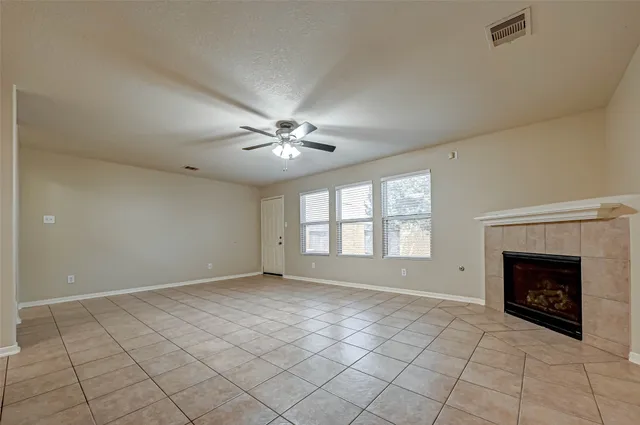a view of an empty room with chandelier fan and fire place