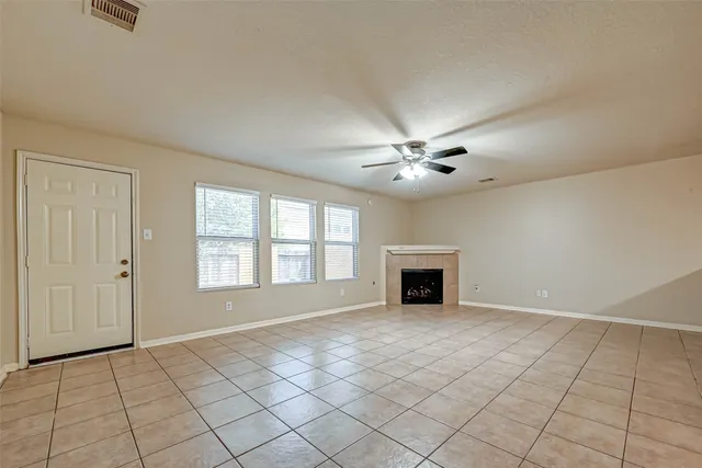 an empty room with windows and chandelier fan