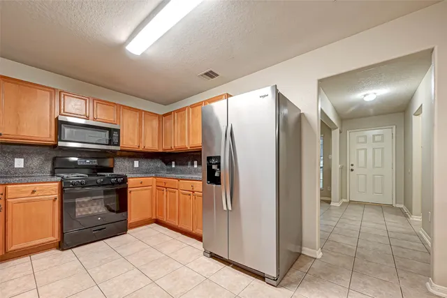 a kitchen with stainless steel appliances granite countertop a refrigerator and a stove top oven