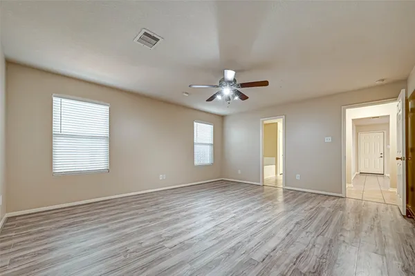 a view of an empty room with wooden floor and a window