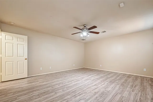 an empty room with wooden floor chandelier fan and windows