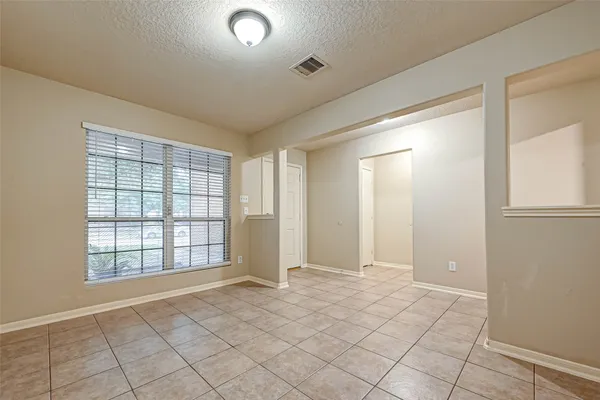a view of an empty room with window and chandelier fan
