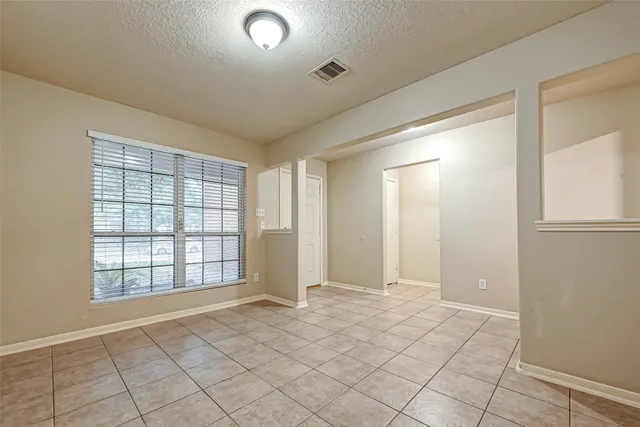 a view of an empty room with window and chandelier fan