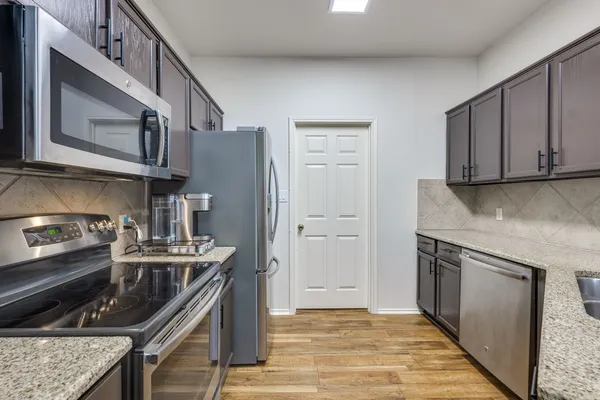 a kitchen with stainless steel appliances granite countertop a sink and dishwasher with wooden cabinets