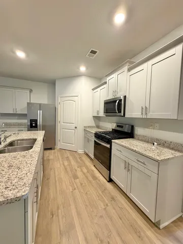 a kitchen with granite countertop a sink stove and refrigerator