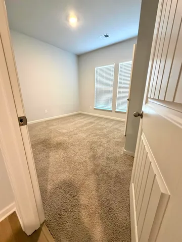 a view of a hallway with wooden floor and a bathroom