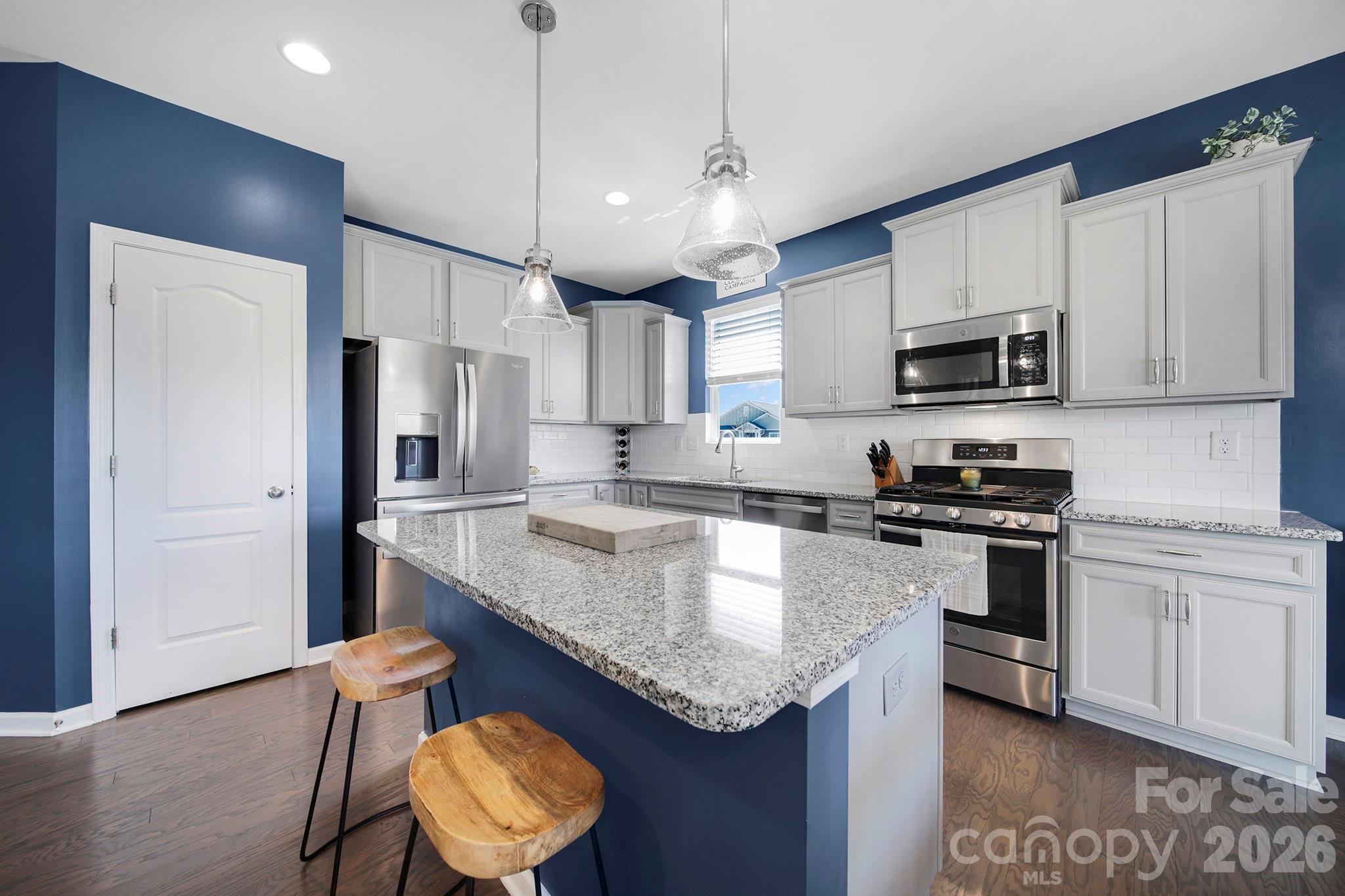 2217 Attaran Lane Lancaster, SC 29720 - Photo 7 of 25 a kitchen with stainless steel appliances granite countertop a sink a stove a refrigerator and island with wooden floor