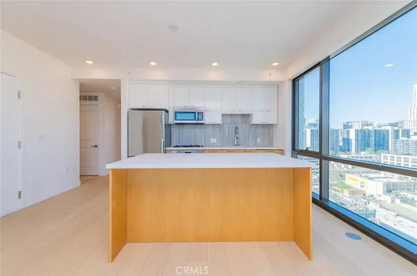 a large kitchen with stainless steel appliances a large counter top a stove and a refrigerator