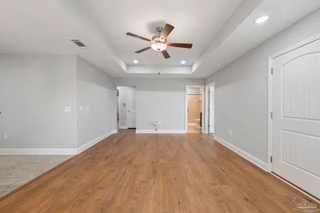 a view of an empty room with wooden floor and window