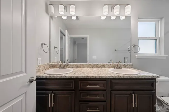 a bathroom with a granite countertop sink a toilet and shower
