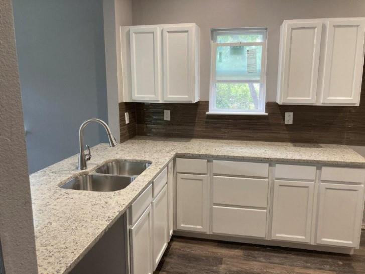 809 South Travis Avenue Denison, TX 75021 - Photo 5 of 13 a kitchen with granite countertop white cabinets and sink