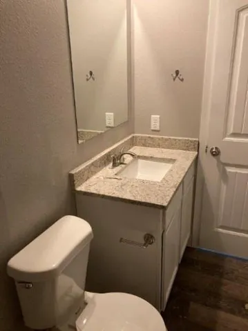 a bathroom with a granite countertop toilet sink and mirror