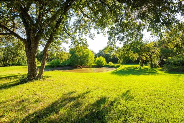 a view of swimming pool with trees in front of house