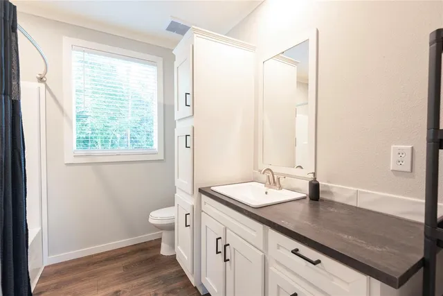a bathroom with a granite countertop sink a toilet a large mirror and shower