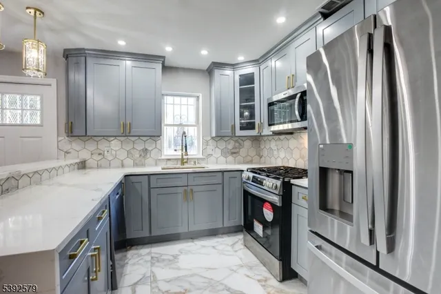 a kitchen with kitchen island granite countertop stainless steel appliances cabinets a sink and a counter top space
