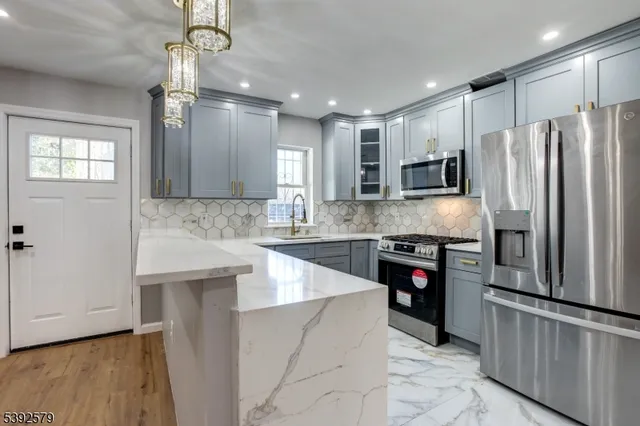 a kitchen with kitchen island granite countertop a refrigerator a sink and a stove