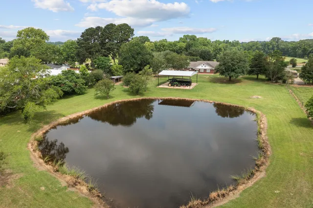 a view of a lake with a yard and large trees