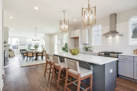 a kitchen with stainless steel appliances a table chairs stove and wooden floor