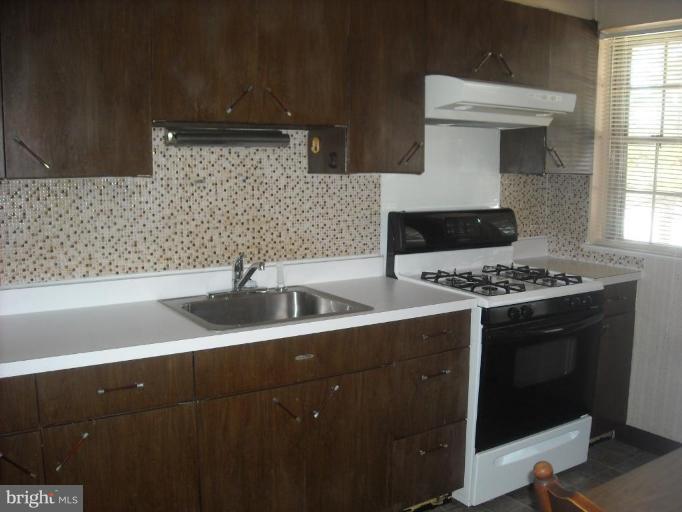 5741 Edgepark Road Baltimore, MD 21239 - Photo 9 of 16 a kitchen with a sink a stove and cabinets