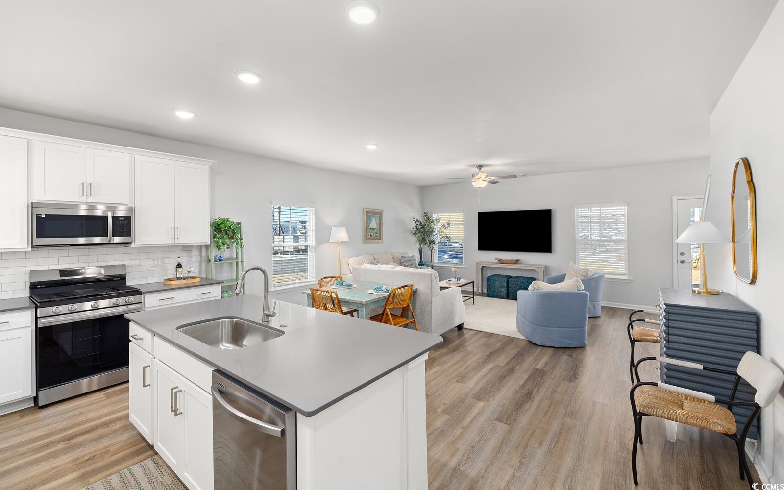 283 Ferretti Street, Unit CONCORD Myrtle Beach, SC 29579 - Photo 33 of 34 Kitchen featuring appliances with stainless steel finishes, a sink, open floor plan, ceiling fan, and tasteful backsplash
