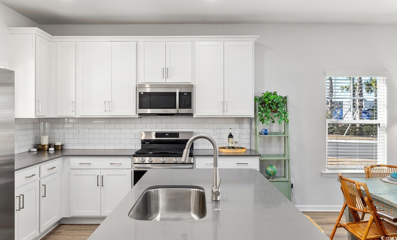 283 Ferretti Street, Unit CONCORD Myrtle Beach, SC 29579 - Photo 5 of 34 Kitchen with appliances with stainless steel finishes, a sink, decorative backsplash, and white cabinetry