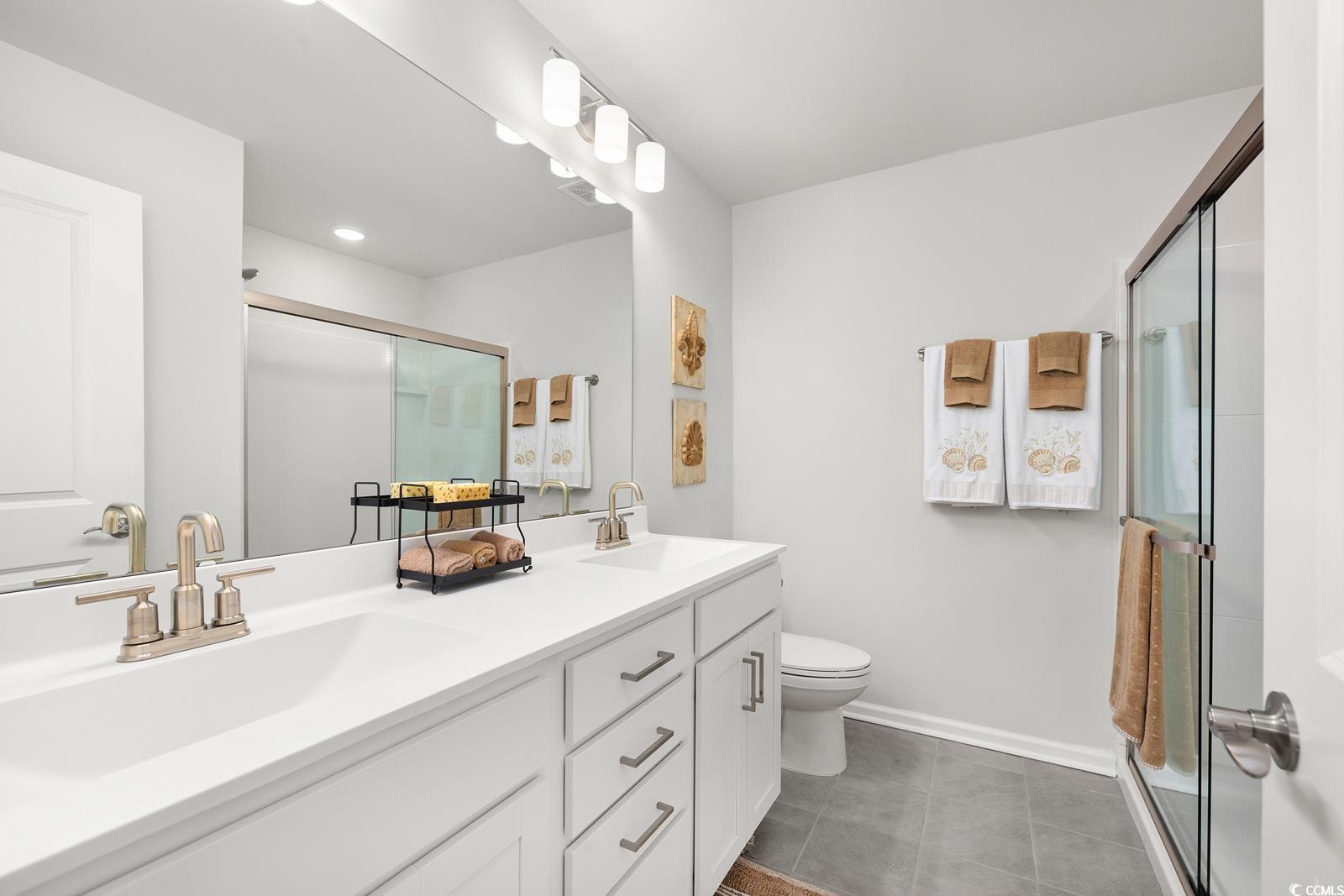 283 Ferretti Street, Unit CONCORD Myrtle Beach, SC 29579 - Photo 8 of 34 Full bath featuring a stall shower, toilet, double vanity, tile patterned flooring, and baseboards