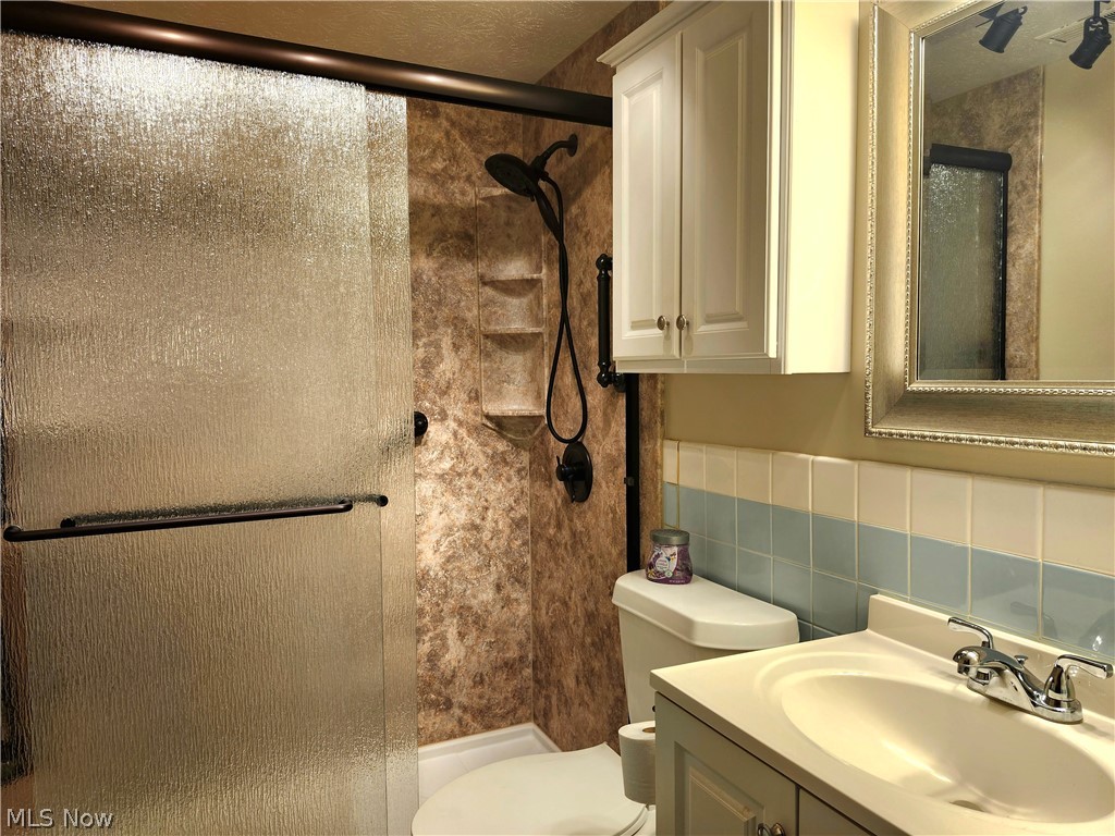 6488 State Road, Unit B 12 Cleveland, OH 44134 - Photo 21 of 46 Bathroom featuring tile walls, tasteful backsplash, walk in shower, toilet, and vanity