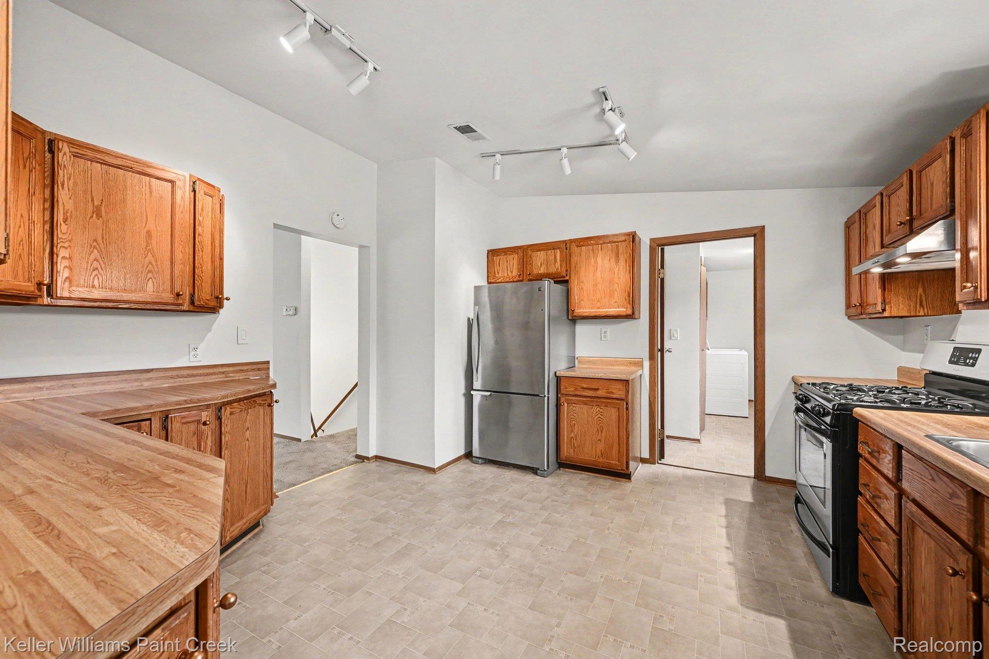 2232 London Bridge Drive Rochester, MI 48307 - Photo 12 of 26 Kitchen featuring wood-finish cabinetry, wood-finish countertops, stainless steel refrigerator, gas range, and track lighting