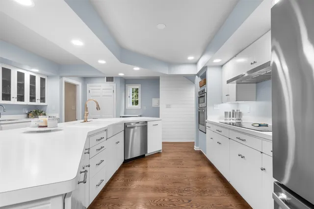 a large white kitchen with granite countertop a lot of white cabinets and a dishwasher