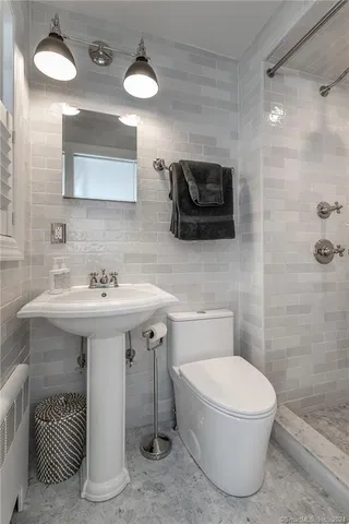 a bathroom with a sink a toilet and shower