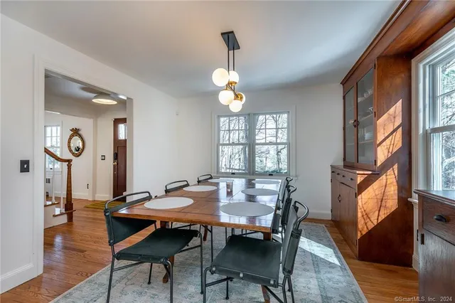 a dining room with wooden floor a chandelier a wooden table and chairs