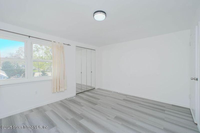 23 Vogel Loop Staten Island, NY 10314 - Photo 20 of 24 an empty room with wooden floor and windows