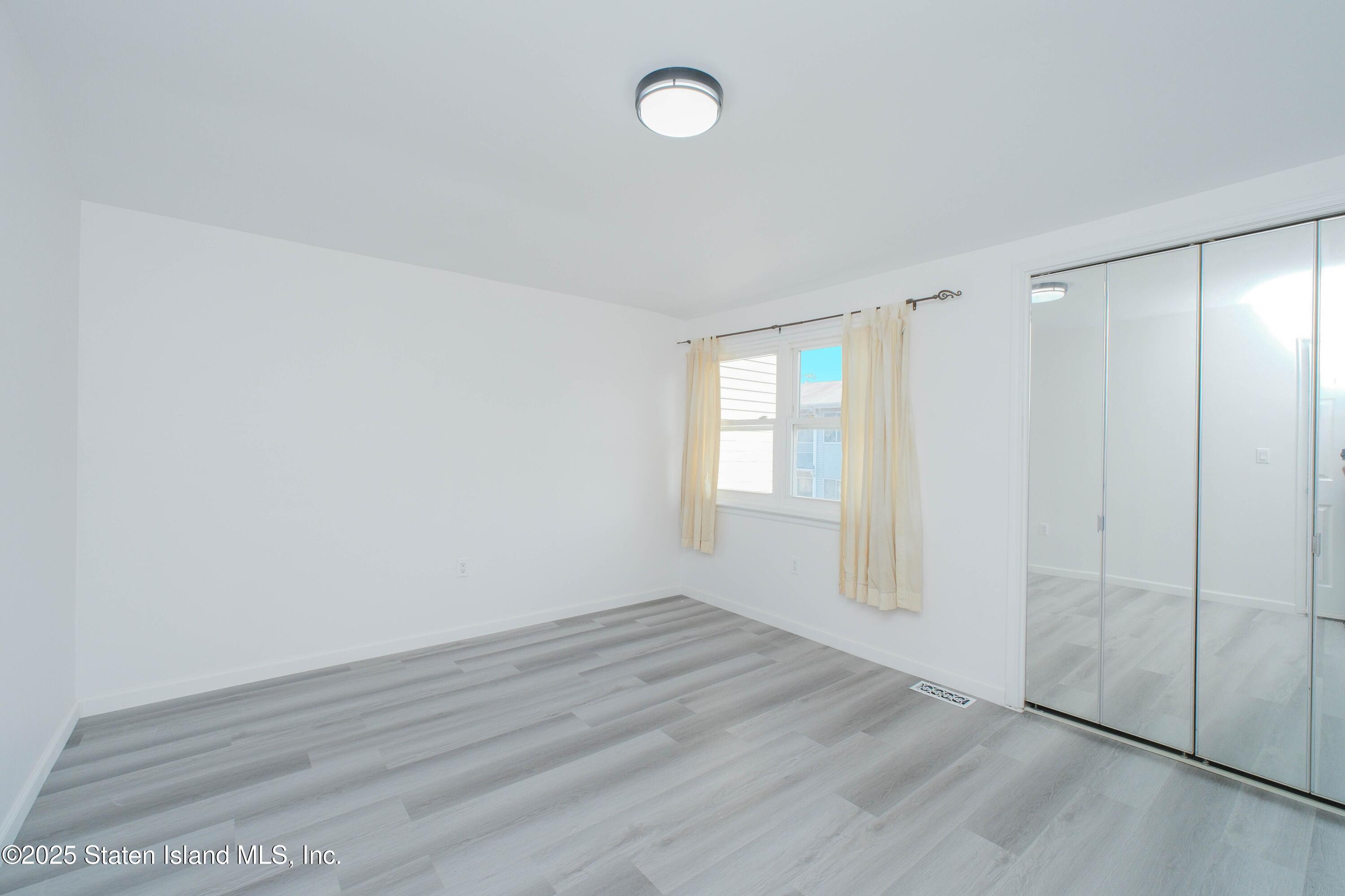 23 Vogel Loop Staten Island, NY 10314 - Photo 21 of 24 wooden floor in an empty room with a window