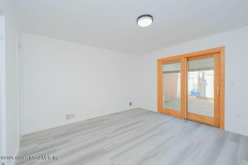 23 Vogel Loop Staten Island, NY 10314 - Photo 4 of 24 an empty room with wooden floor and windows