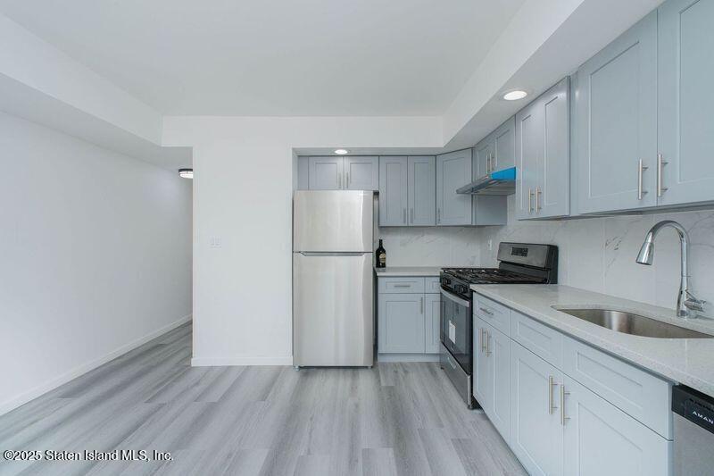 23 Vogel Loop Staten Island, NY 10314 - Photo 9 of 24 a kitchen with a sink a refrigerator and white cabinets