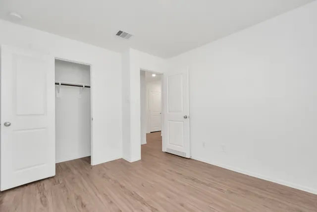 a view of an empty room with wooden floor and closet