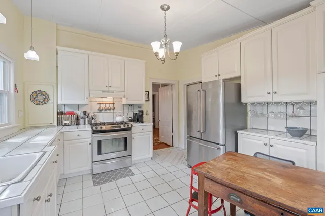 a kitchen with kitchen island granite countertop a stove a sink and a refrigerator with white cabinets